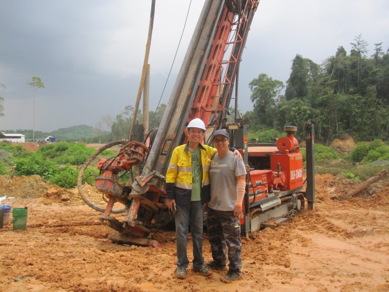 Two miners standing in front of drilling equipment