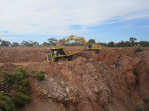 Digger emptying scoop into truck at mine site